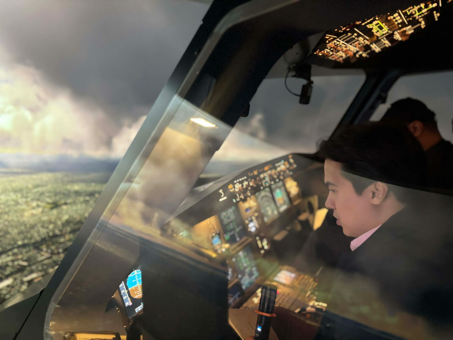 A colleague seated at the Airbus A320 simulator flight deck controls during a Flight Deck Challenge session, city lights visible through the windscreen